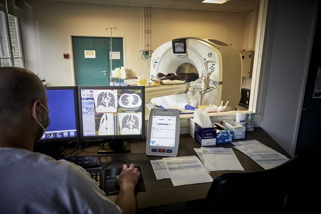 Un manipulateur radio regarde les clichés du scanner pendant qu'un patient de Bligny est allongé dans le scanner.